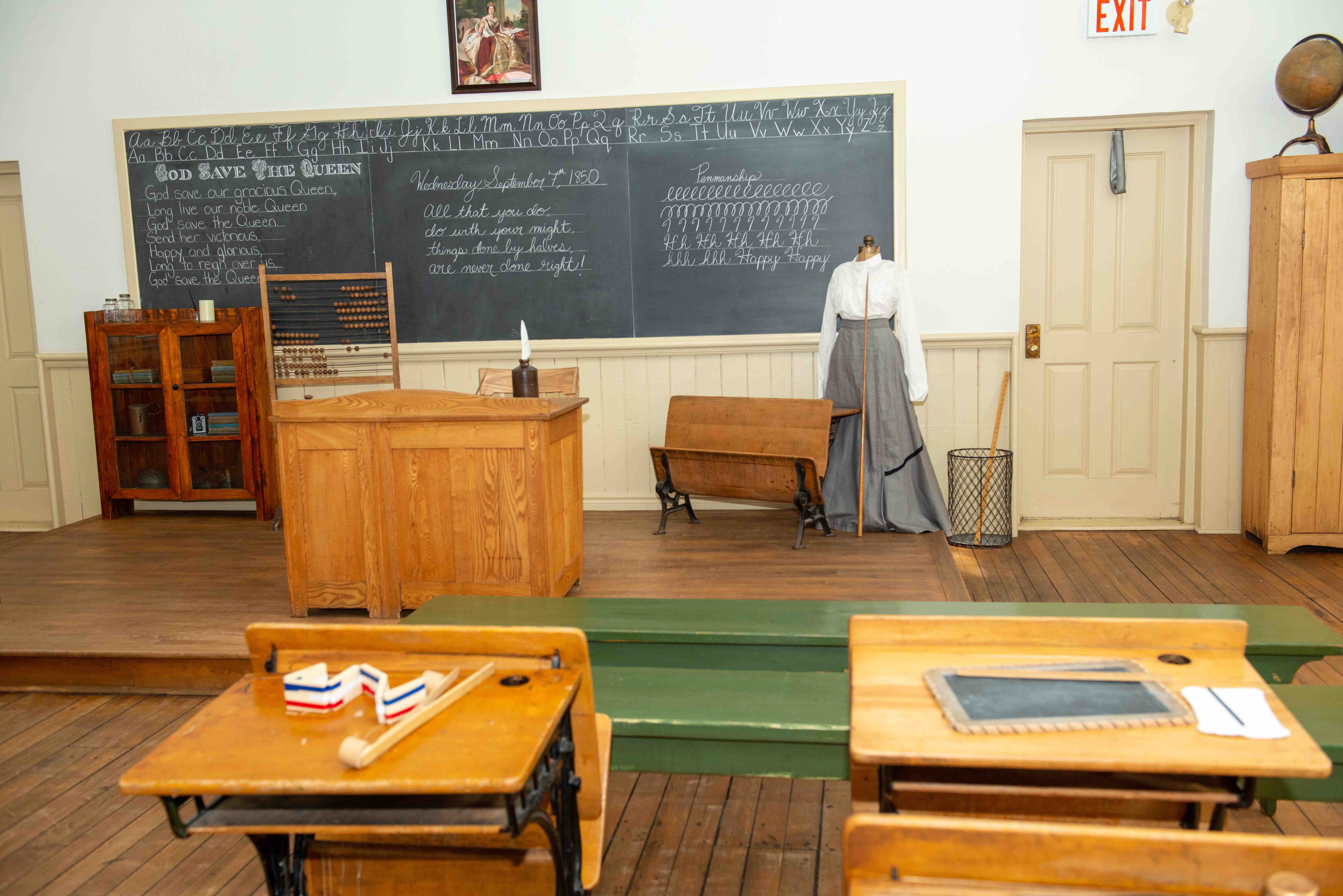 Museum classroom photograph with desks and chalkboard