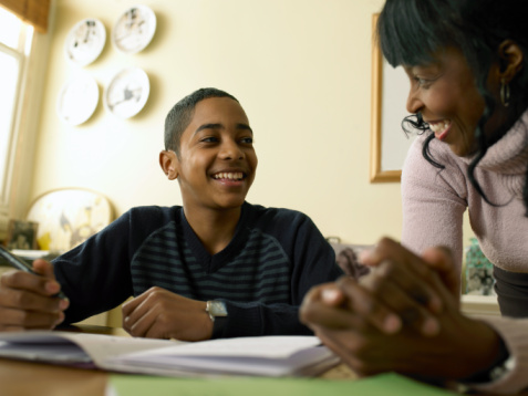 Student sitting at table doing homework with adult female