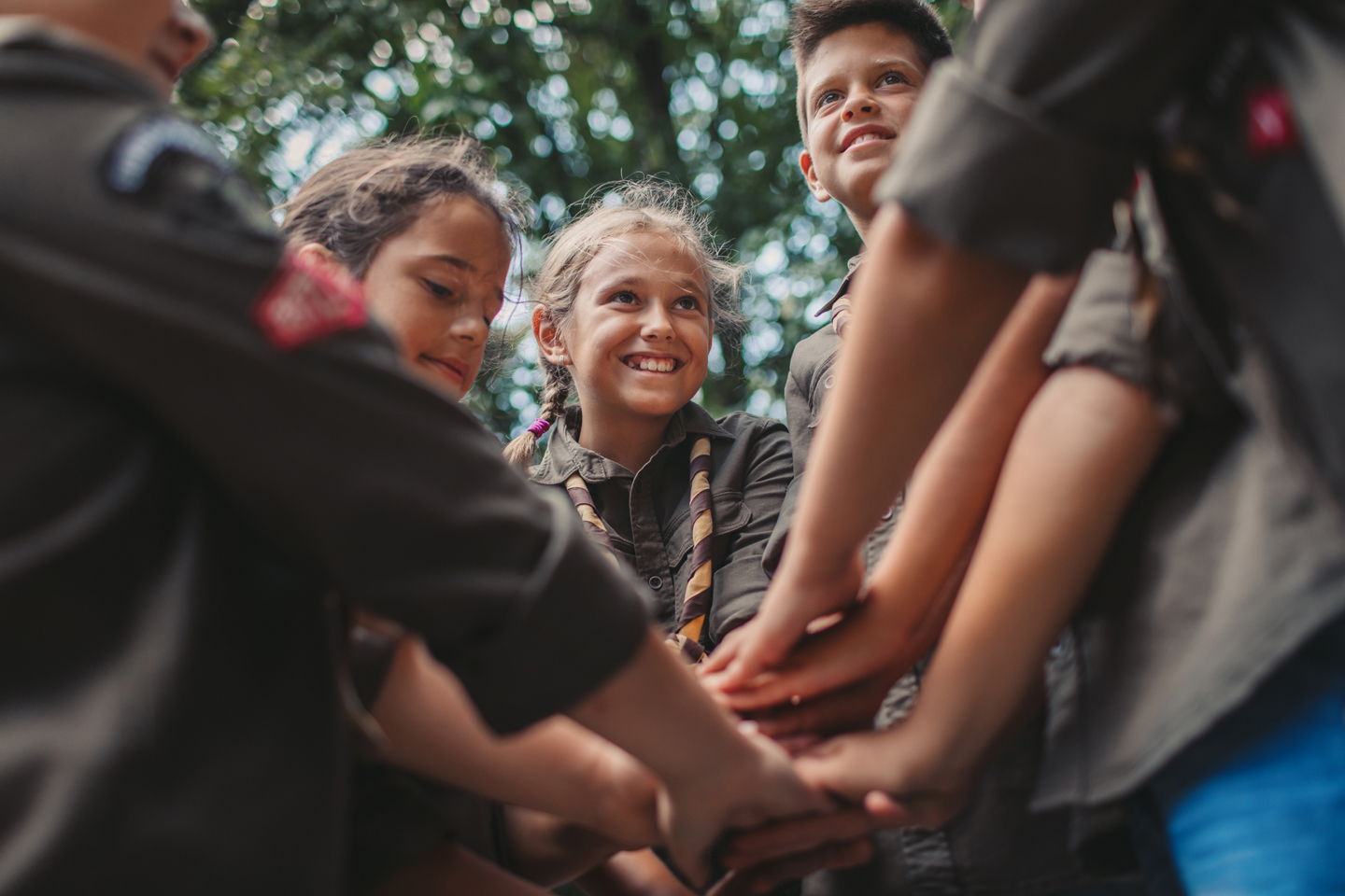 Students outdoors gathered with hands put together