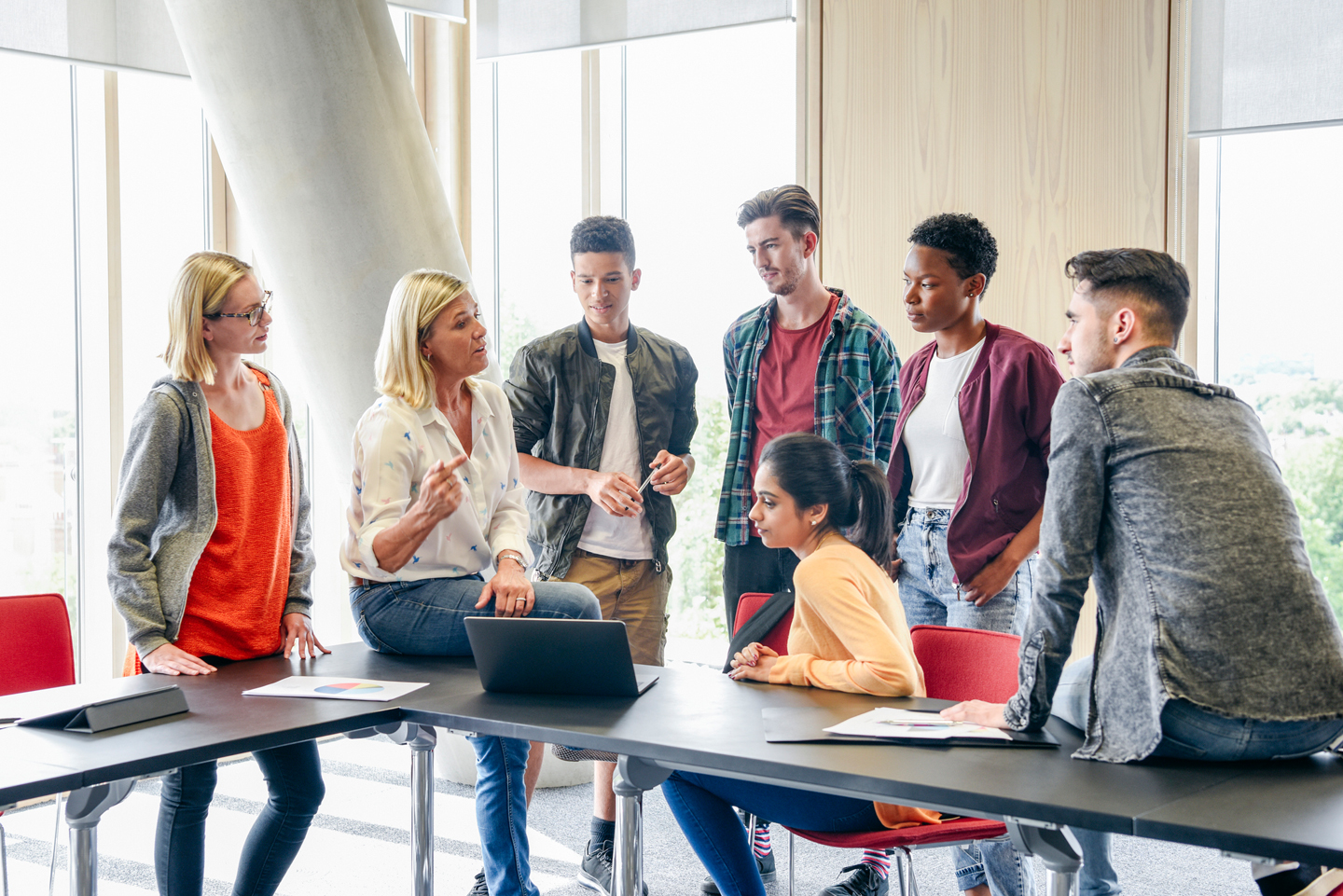 Students looking at laptop and teacher