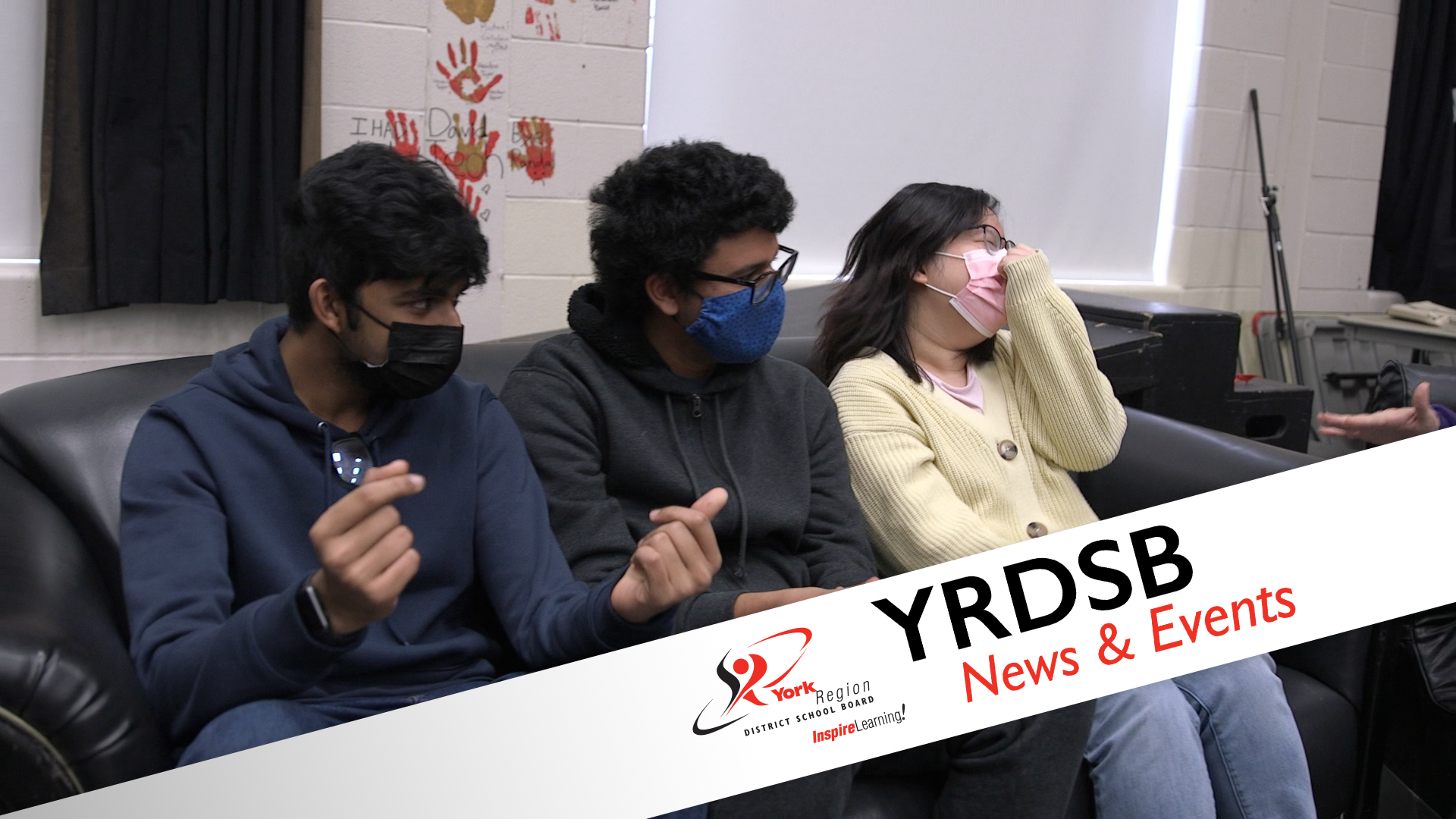 Three students sitting on couch wearing masks