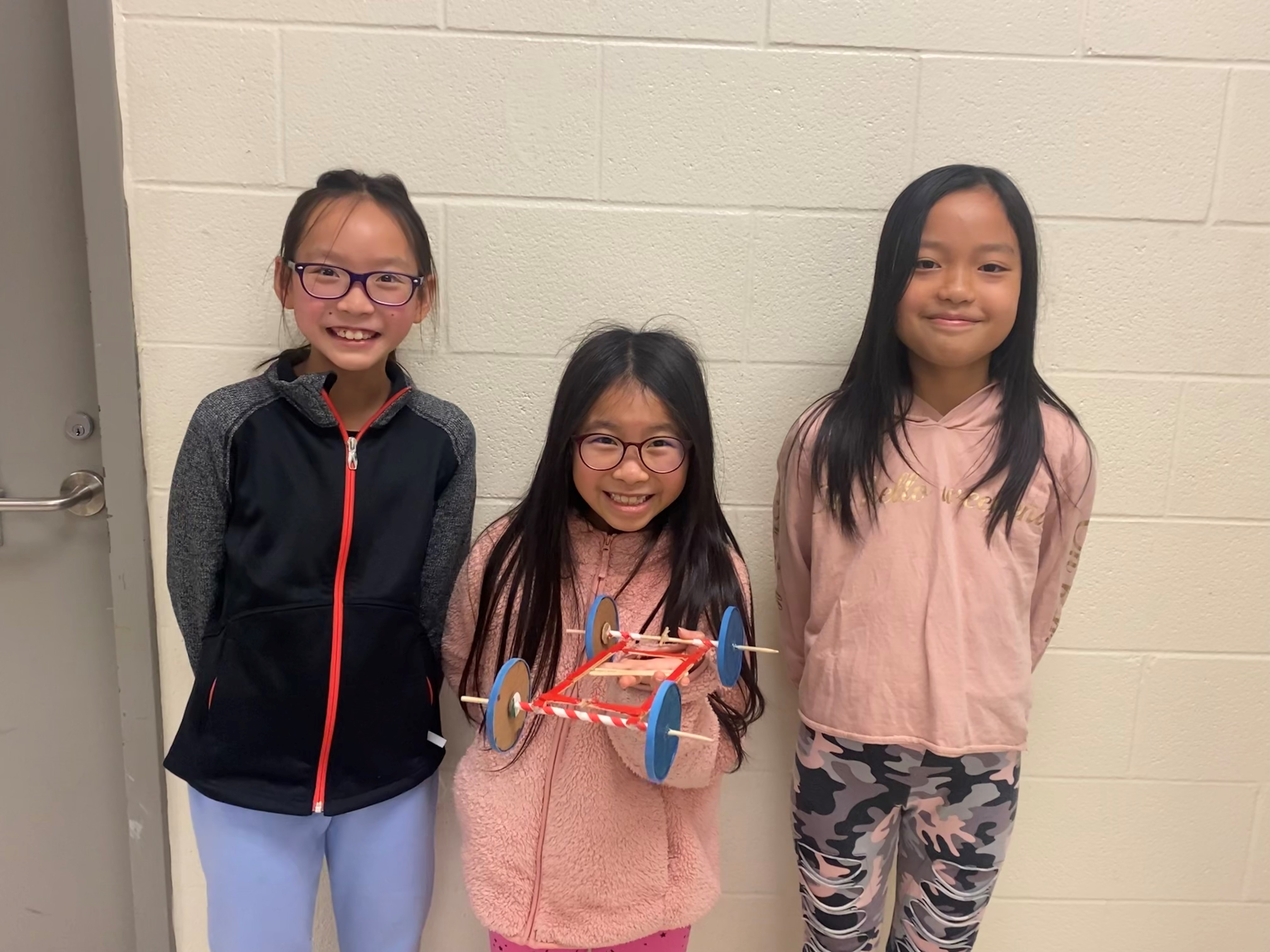 Three students with their cardboard car