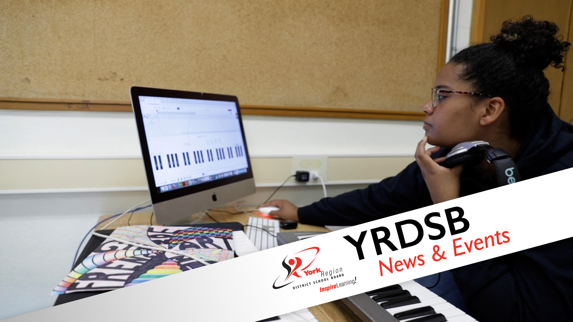 Student holding headphones looking at laptop with music program running