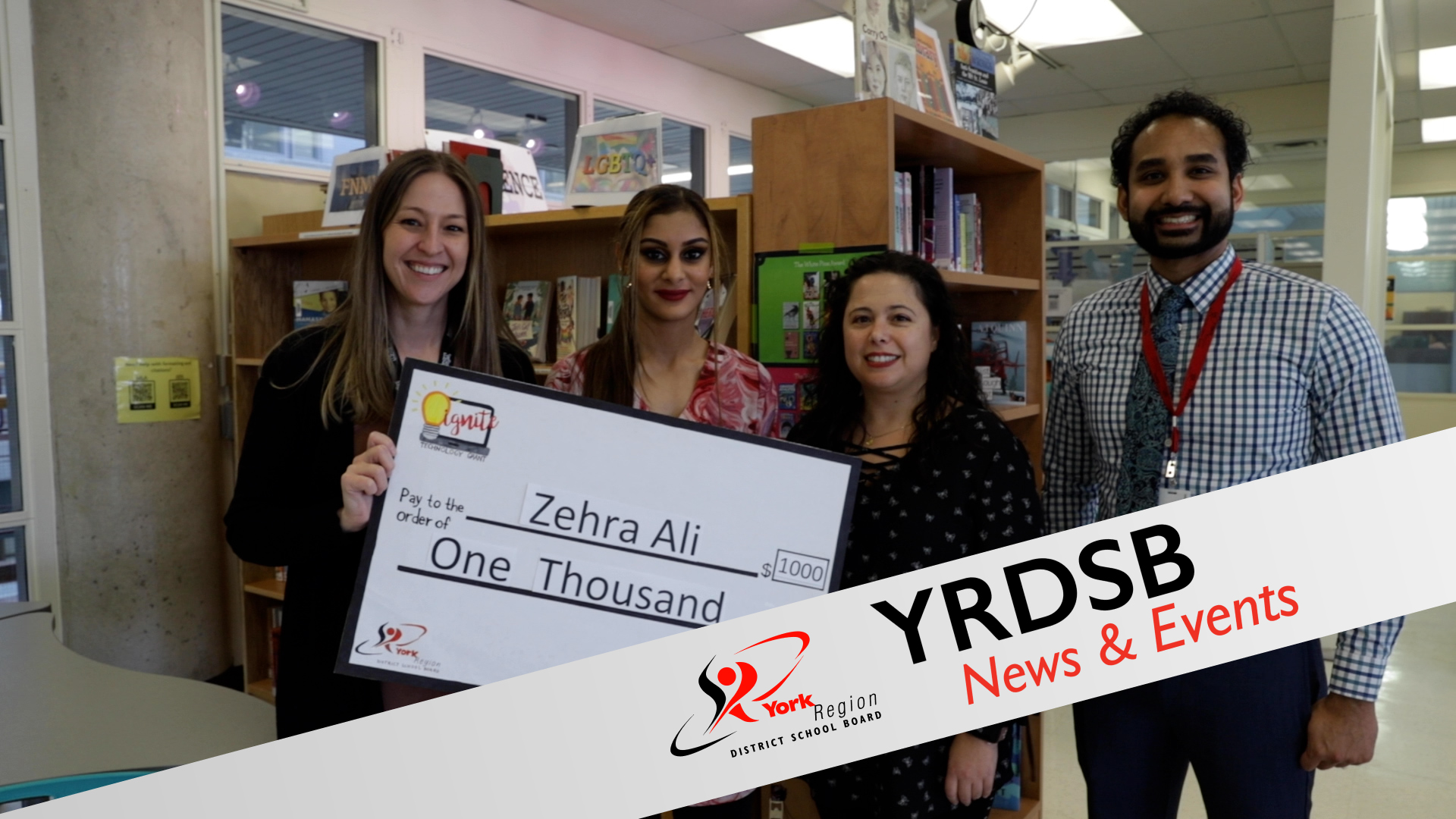 Students and adults holding large check for $1000 in school library