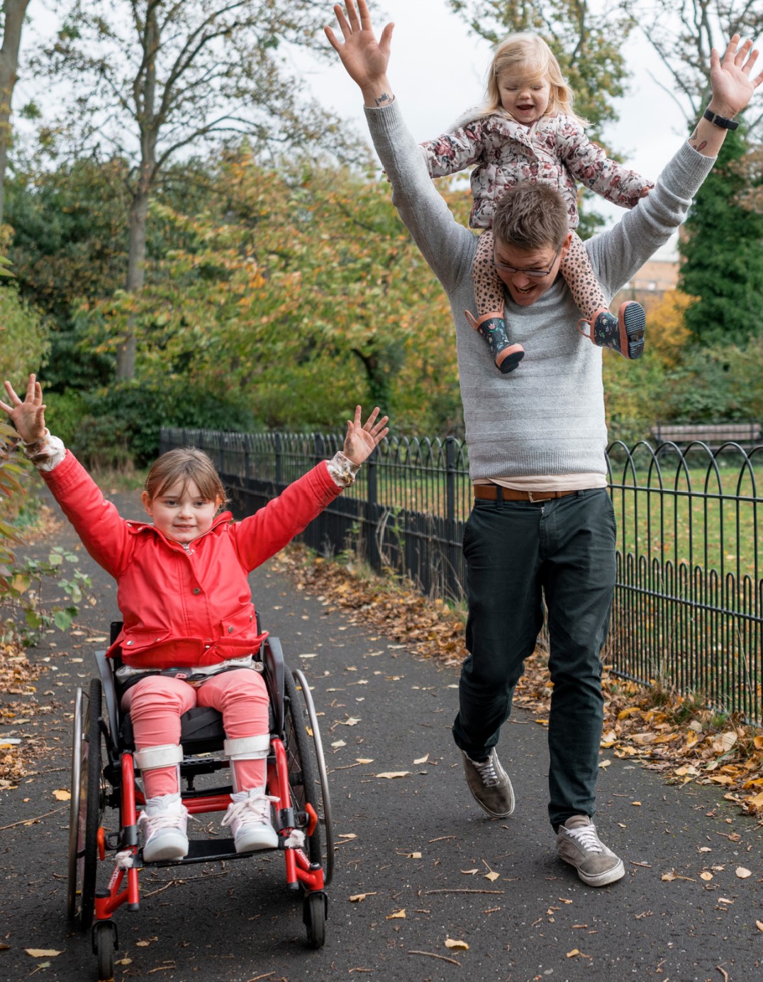Student in wheelchair with another child on the back of an adult