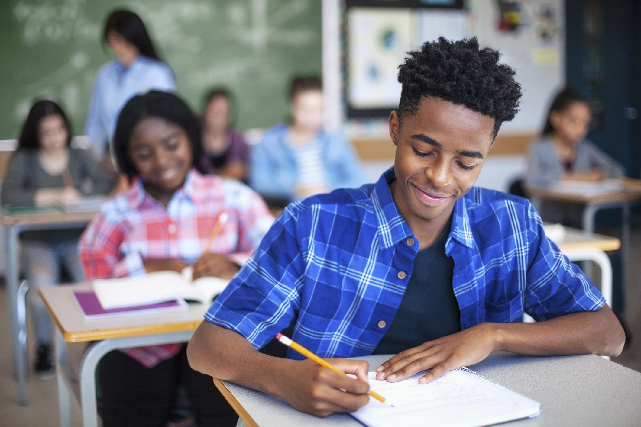 secondary student writing in classroom