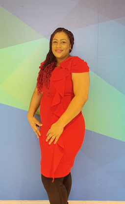 Image of Candice Chang-Sandy, a black woman dressed in a red short sleeve dress with black tights.