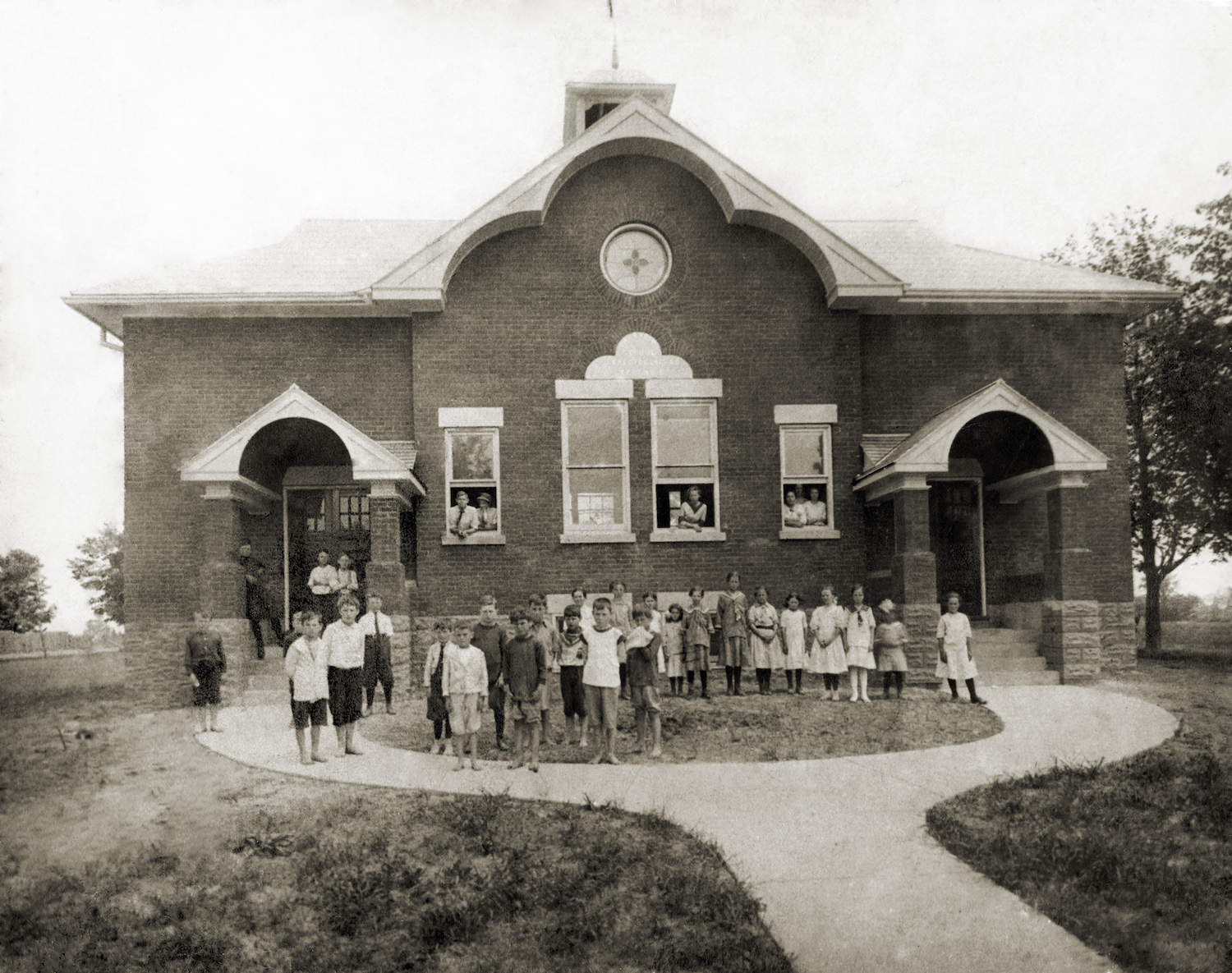 black and white photograph of exterior of school with children
