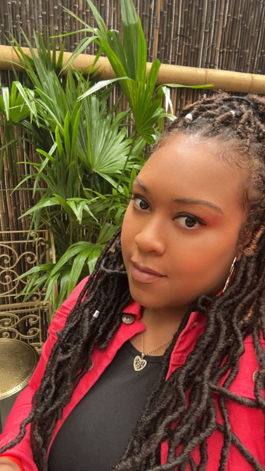 Image of Tamara Hamilton, a black woman dressed in a black shirt with a red blazer over top.