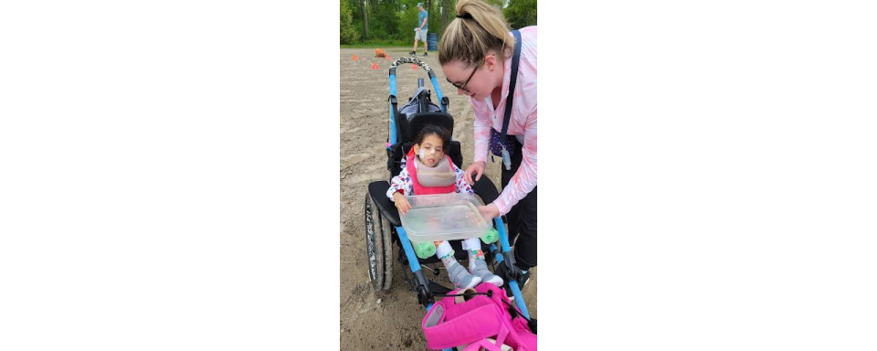 Student in wheelchair participating in the outdoor learning activity with a staff member.