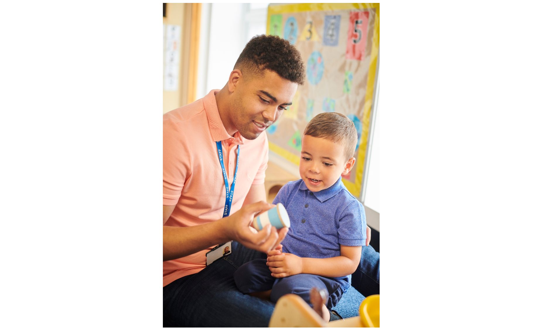 Teacher playing with young student in classroom.