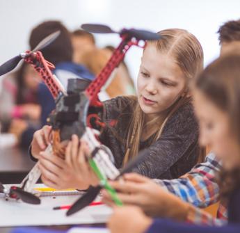 Elementary students looking at drone