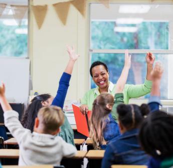 Children with hands up in class
