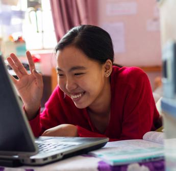 Student waving on laptop