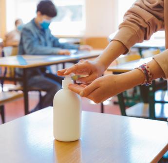 Student using hand sanitizer in classroom