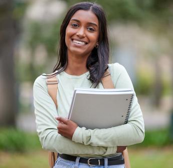 Smiling secondary school student holding notebook