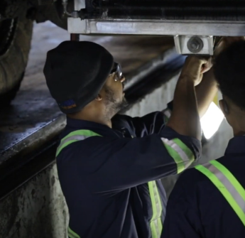 Two men work beneath a car 