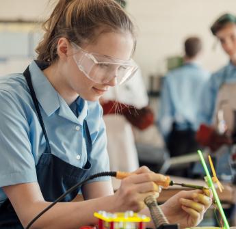 female secondary student soldering wires in class
