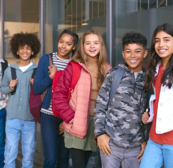 secondary students leaning on wall backpack outside