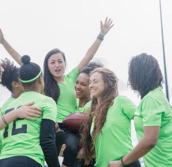 secondary students lifting up teammate on football field