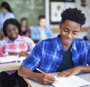 secondary student writing in classroom