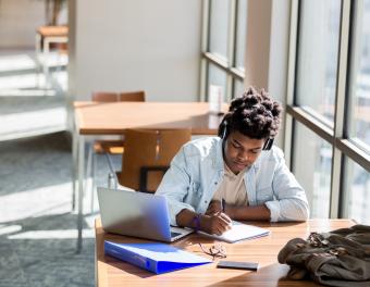 Student working with technology and writing