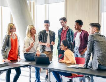 Secondary students listening to teacher with laptop