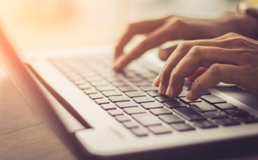 Hands typing on laptop keyboard