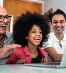 Family of three looking at a laptop and smiling.