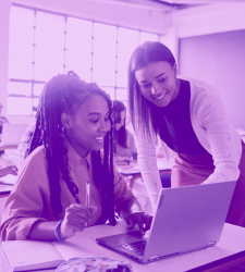 Student and teacher look at computer screen. Image has purple tint to it. 