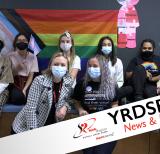 Staff and students in front of rainbow flag