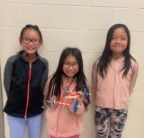 Three students with their cardboard car