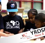 Three young Black students working with educator at a table