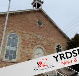 Stone schoolhouse building with flagpole outside. Banner across the bottom reads YRDSB news and events