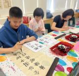 Three students seated at a table writing in calligraphy