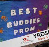 Blue background covered in orange and green handprints reads Best Buddies Prom