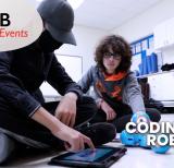Students sit on floor with tablet and robot