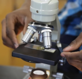 Student holds slide on mircroscope
