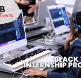 Student wearing headphones sits in front of music keyboard and monitor 
