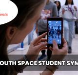 Student holding phone watching students at symposium