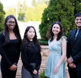 Four students standing outside smiling at the camera