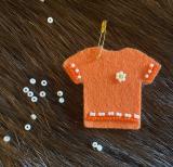 felt orange shirt pin with beading on it appears on fur background with white beads scattered around it