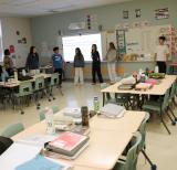 Students stand against the wall around the outside of a classroom