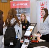 students stand at a booth speaking with representatives. Booth signs reference careers in aviation and aerospace.